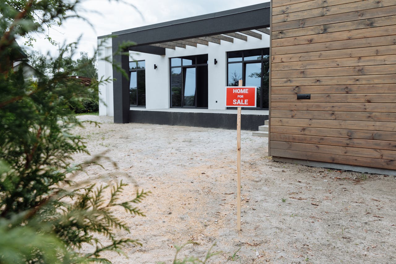 our-story Modern house exterior with a Home for Sale sign in front yard.